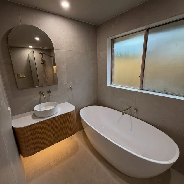Renovated bathroom with a freestanding bath and arched mirror