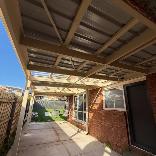 Timber carport frame and roof beside a brick home