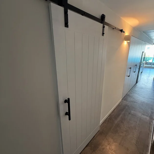 Barn door hung on a panelled wall in a hallway