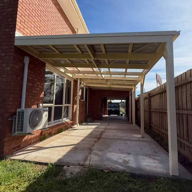 Timber carport with exposed rafters alongside a brick home