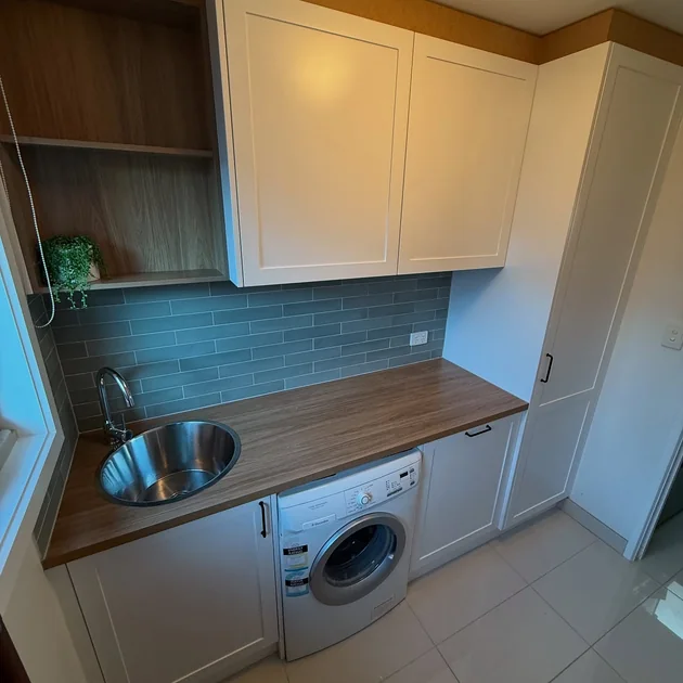 Renovated laundry with overhead cabinetry and a timber bench