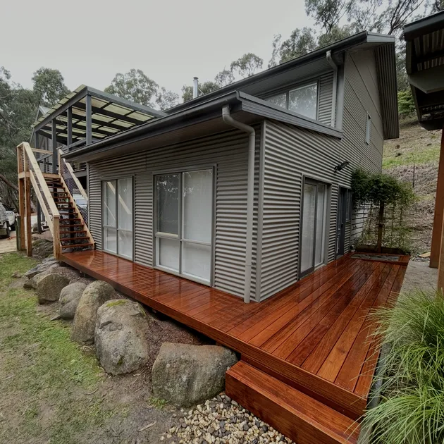 Corrugated clad two storey home with a new merbau deck across the rear