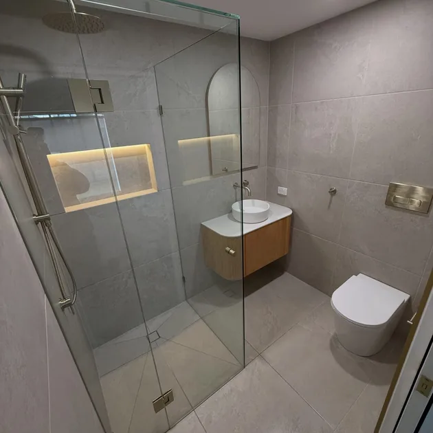 Renovated bathroom with a walk in shower, lit niche and timber vanity